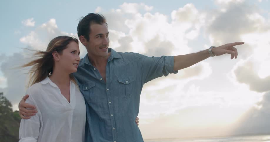 A man and woman taking a romantic walk on a beach on a summer evening