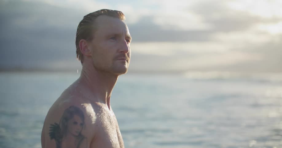 A man stands in the ocean and smiles
