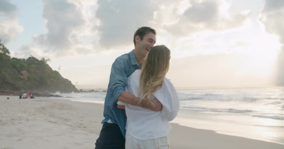 A couple is romancing on a beach with sea behind them