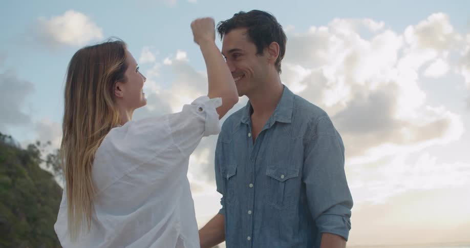 Young couple talking tenderly on a beach next to the ocean at sunset