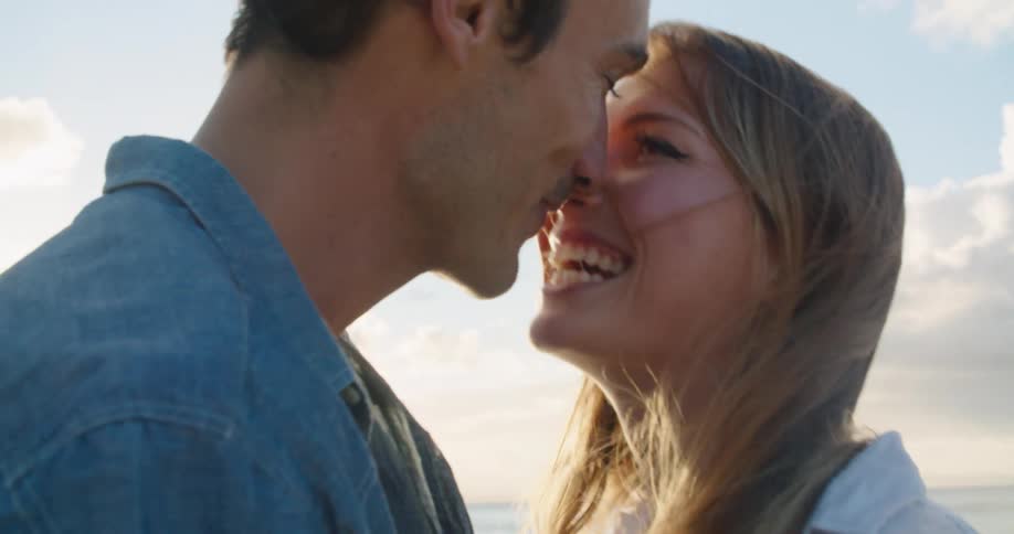 Young couple kissing on the beach at sunset