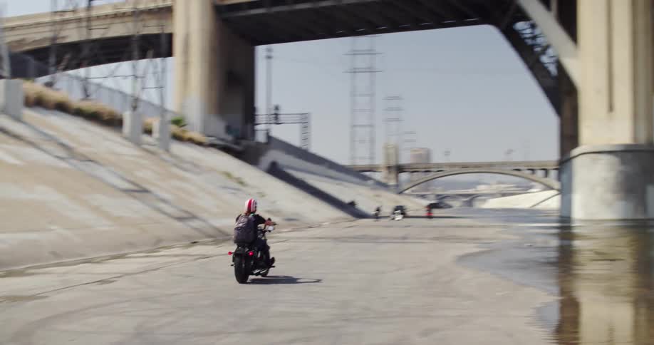 A man rides a motorcycle in the empty waterways of a city