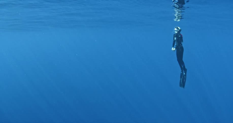 A scuba diver swims towards the surface