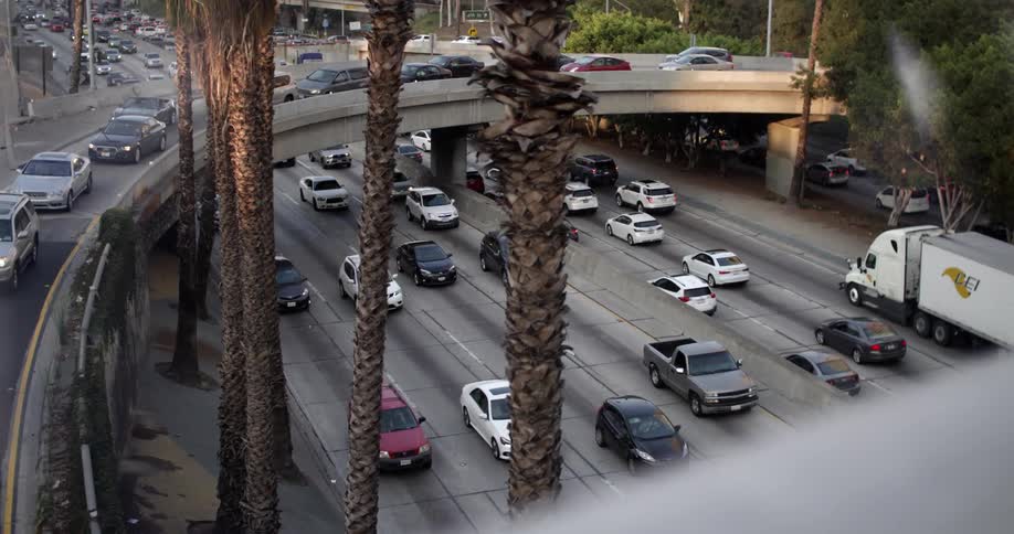Cars stopped in an overpass while many cars travel on the highway below