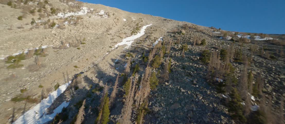 Snow and ice sits in dry hollows on slope of mountain