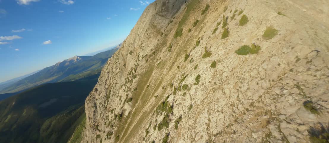 Vegetation dots slope of mountain in mountain range under cloudy sky