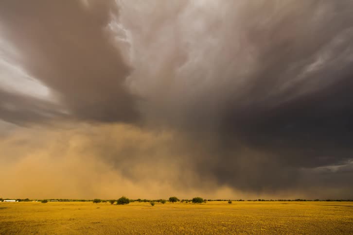 An enormous and powerful storm cloud releases rain onto the ground below