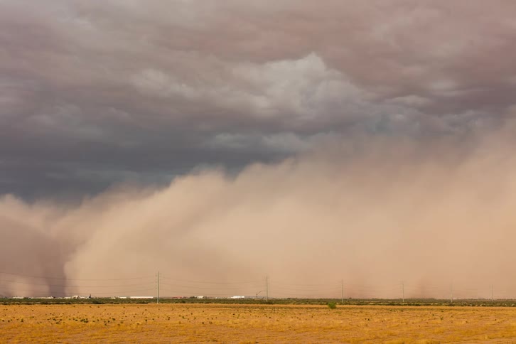 A dense dust cloud obscures a rural town in the desert