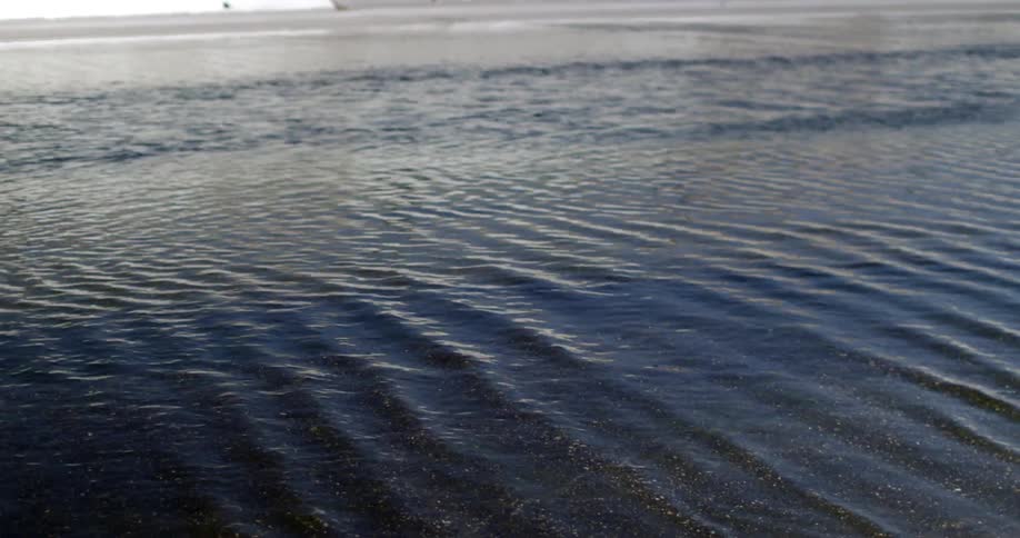 Water running in a river creating ridges in the sand and rocks
