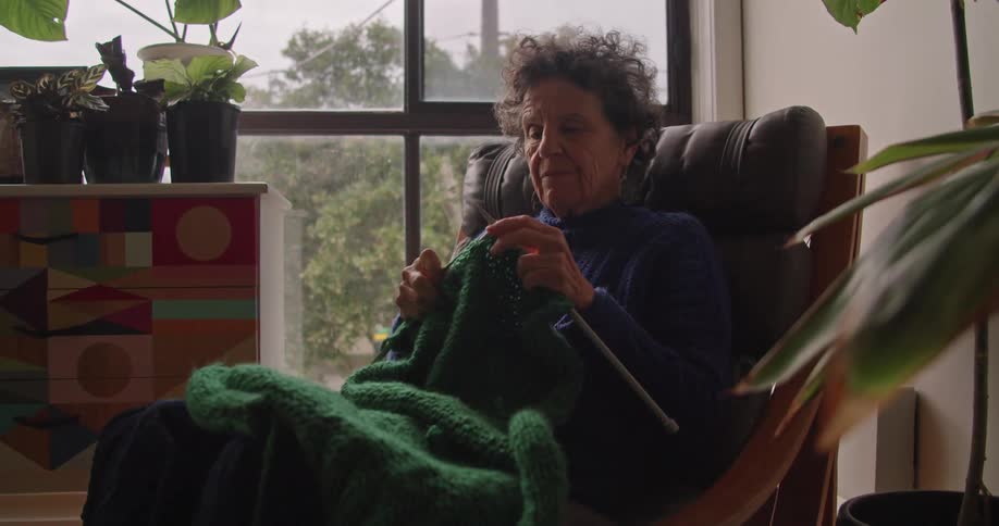 A woman is knitting a blanket at home