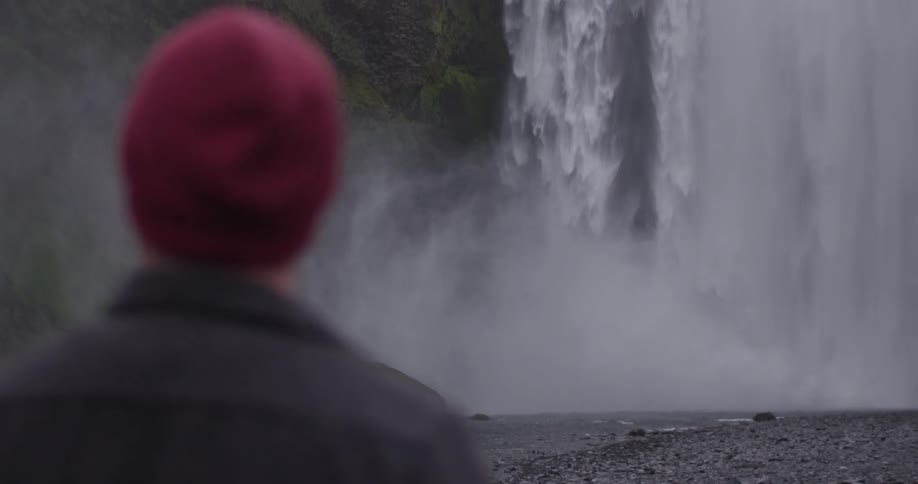 Man watching water falling from a very tall waterfall