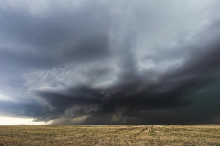 Timelapse of dark storm clouds pouring rain over a field in the countryside