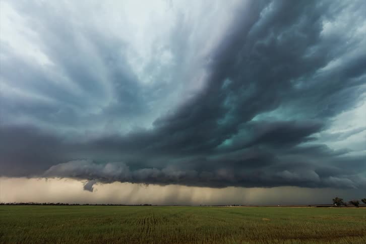 Blue gray storm clouds flow over plains with the occasional lightning bolt as traffic speed by