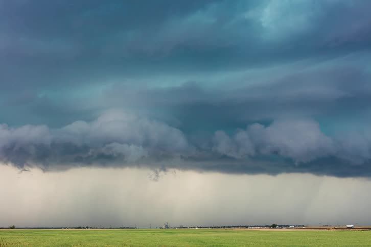 Storm clouds are in rotation above the ground and lightning is flashing