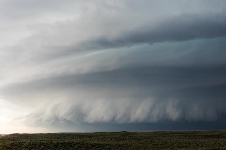 Blue gray storm clouds slowly rotate over plains as lightning strikes
