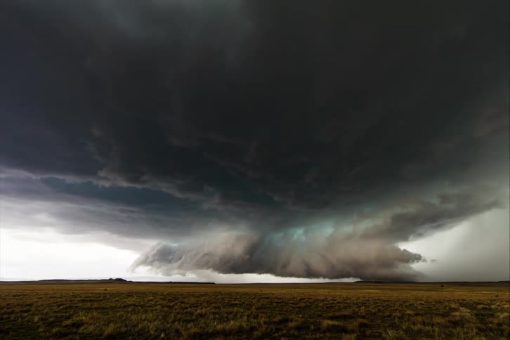 Storm clouds rotate above plain with grass more yellow than green