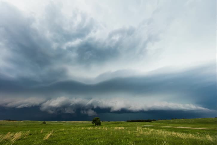 Thick clouds roll over a vast grassland during the day