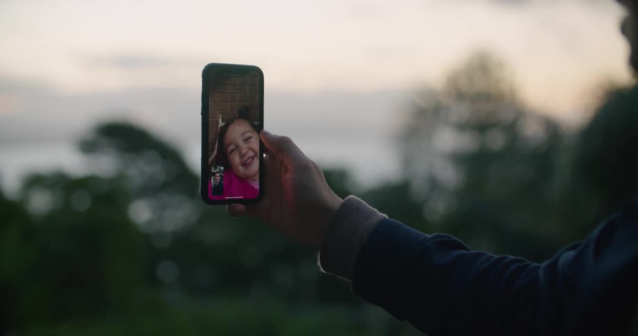 A man video chats on his cell phone with a little girl