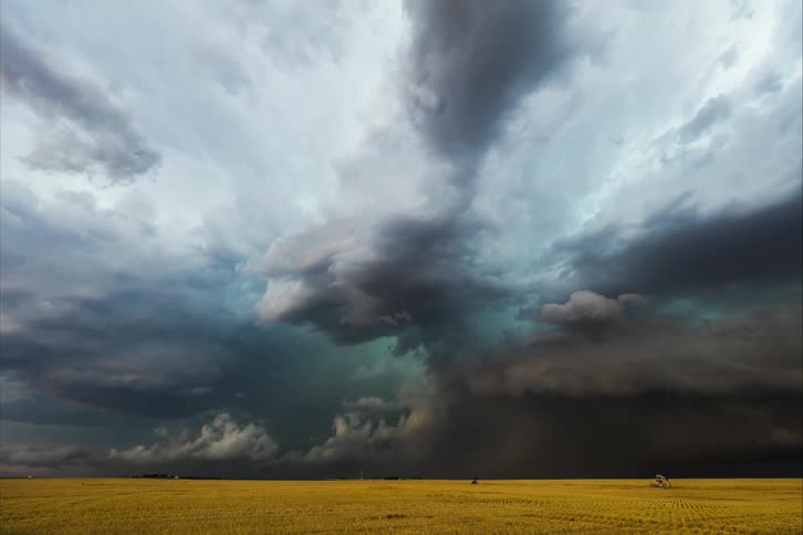 Storm clouds and lightning float over a vast grassland during the day