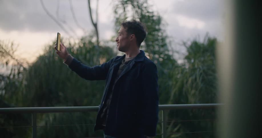 Man greeting someone on a video call on his smartphone at evening