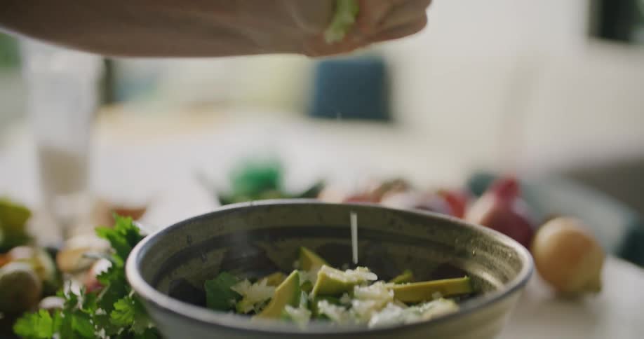 Mans hand squeeze a lemon in a bowl with food in the kitchen