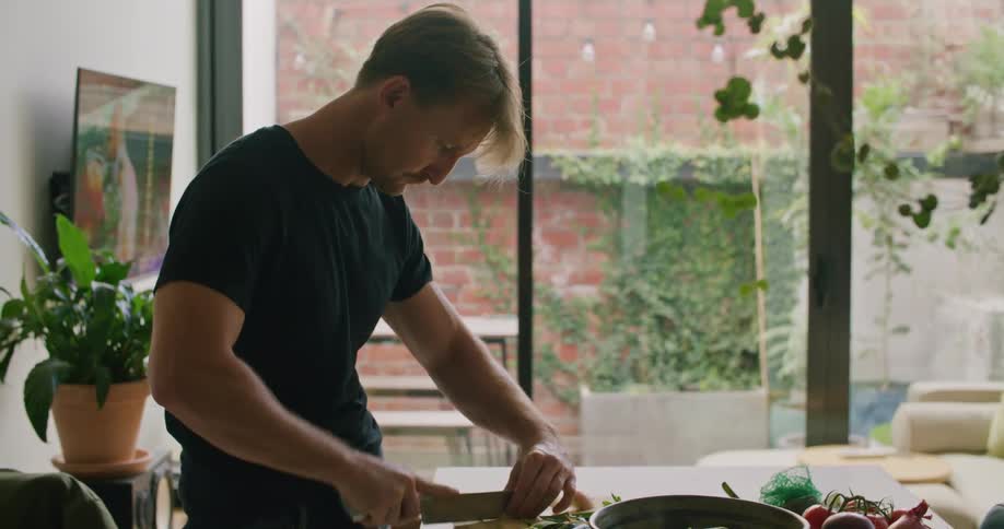 Man chopping vegetables with a sharp knife on the kitchen at home