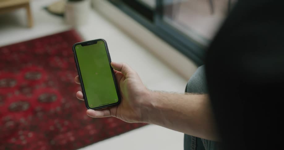 Person sits viewing mobile phone near sliding glass door