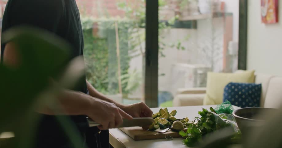 A man cuts avocados into wedges in his kitchen