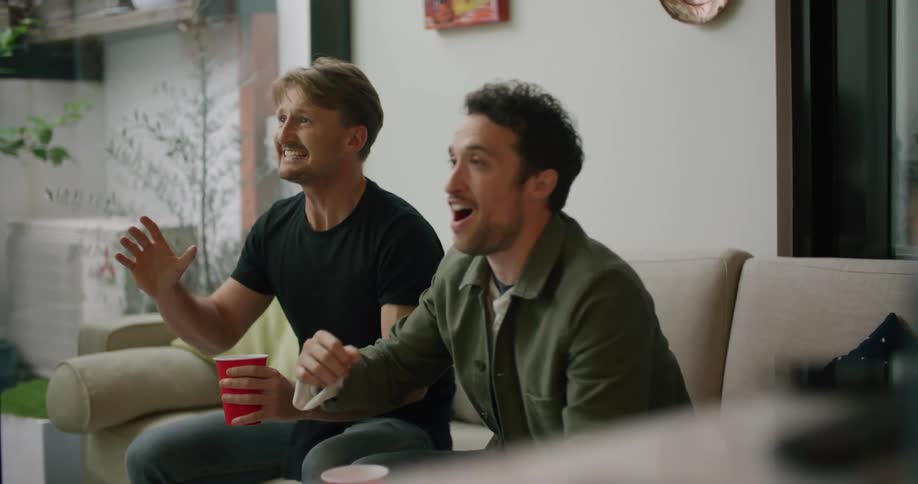 Two men celebrate something they are watching on tv