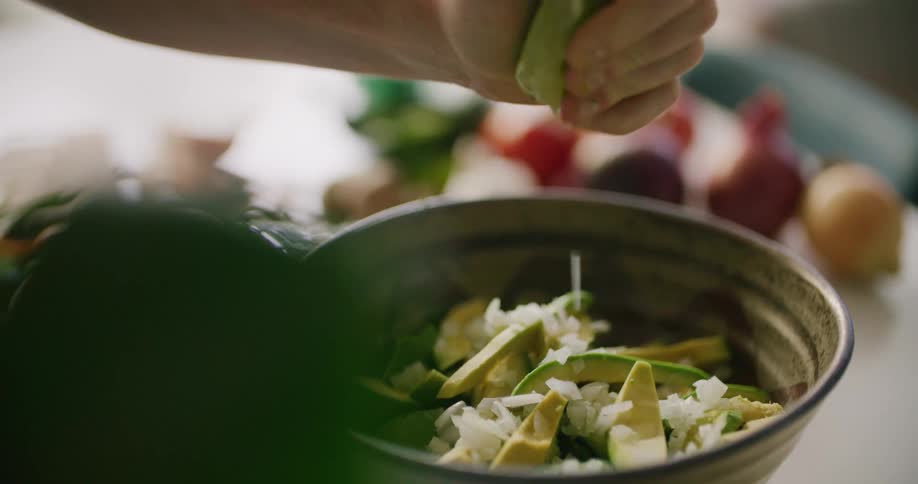 A man squeezes a lime in to a bowl as he cooks