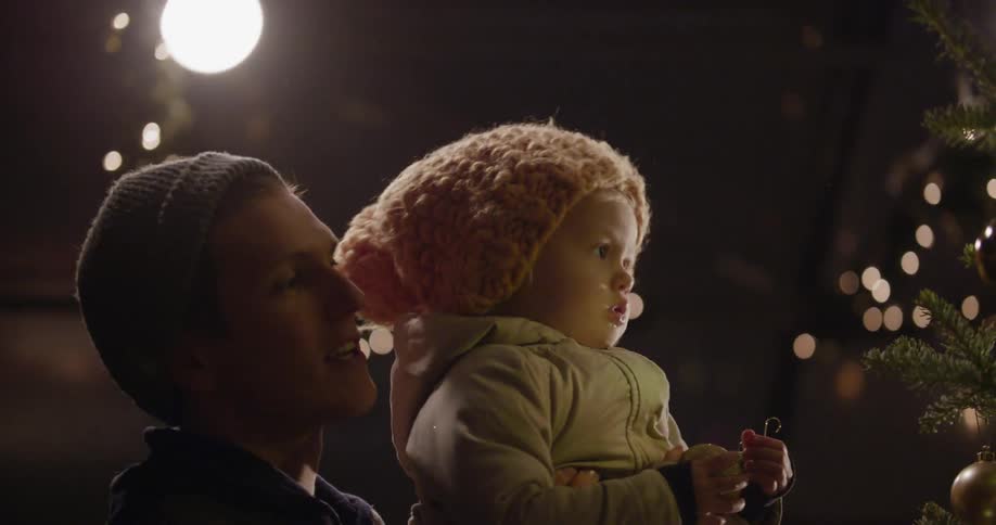 A man picks up his child in front of a christmas tree