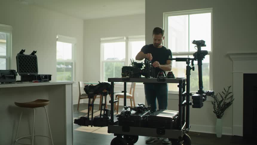 A man places a lens filter on a large professional video camera