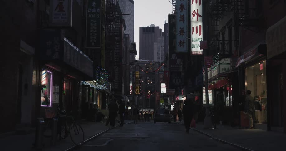 People hand outside businesses and walk down the street in a citys chinatown