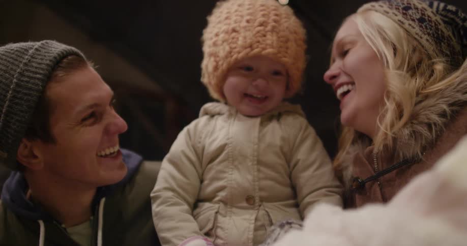 Parents are holding their child and smiling