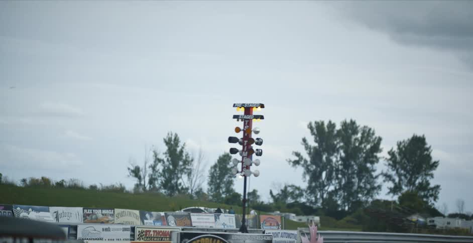 The starting lights on a race track light up as a car waits at the starting line