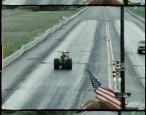 A view of two cars that are drag racing down a dragstrip
