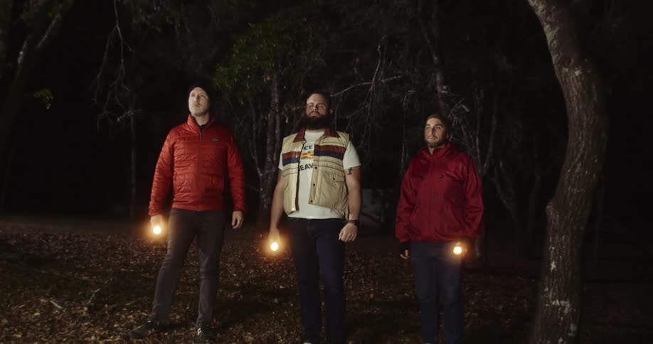 A group of people standing in a forest camping together