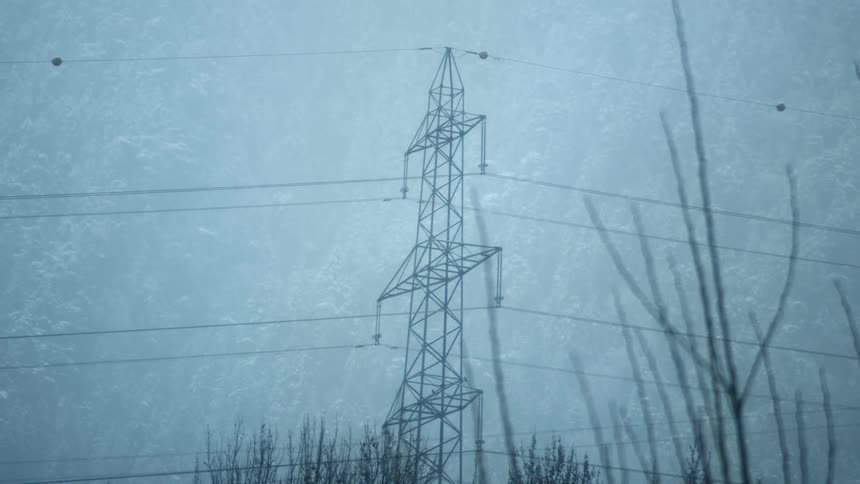 A tiered utility pole sits in a field of tall grass