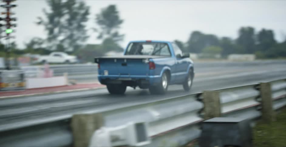 A blue pickup truck takes off speeding down a rural highway