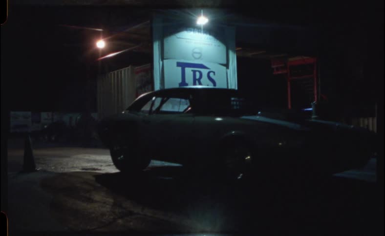A car driving away from a building at night