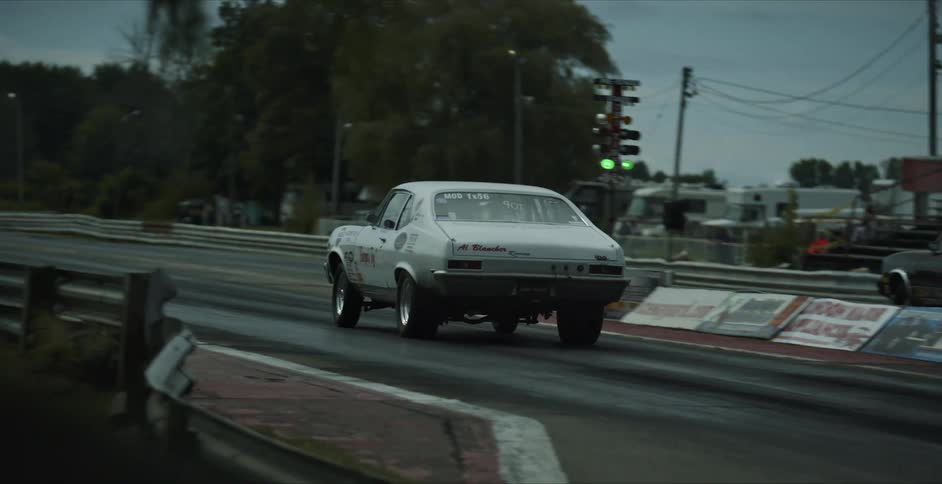 Sports cars race down track after go signal past empty spectator stands