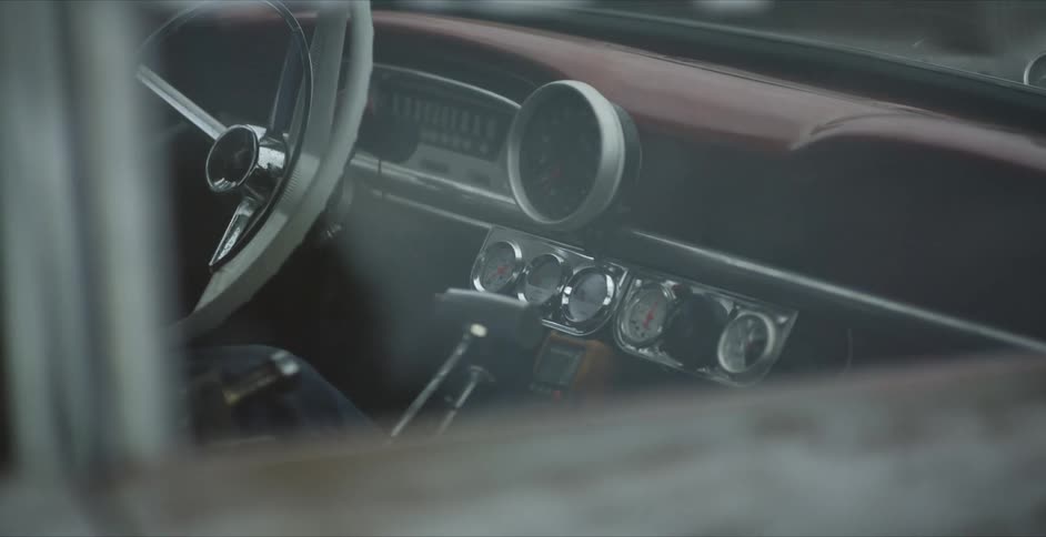 A person sitting in a vehicle with a steering wheel gauges and windows