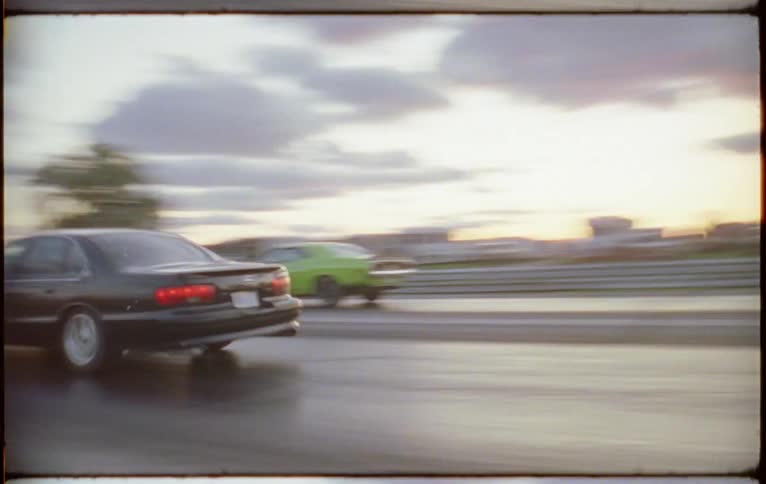 Two muscle cars race down a rural highway