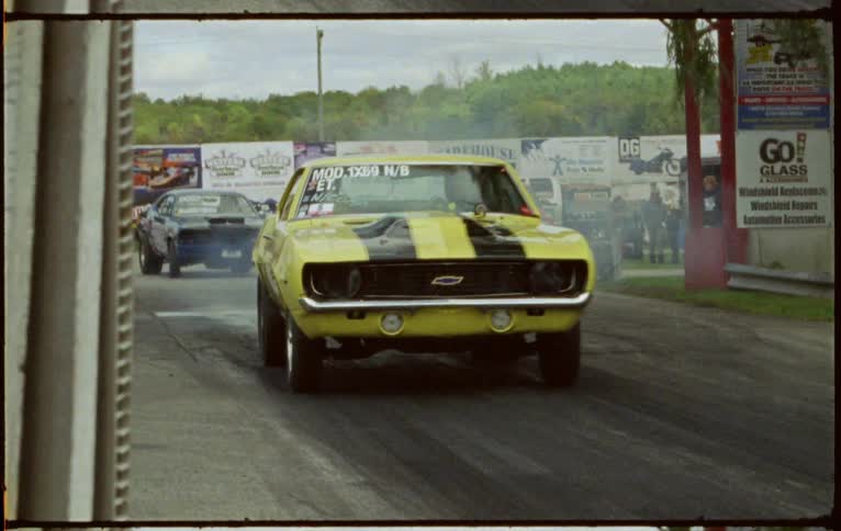 Spectators stand back as race cars drive on to a track