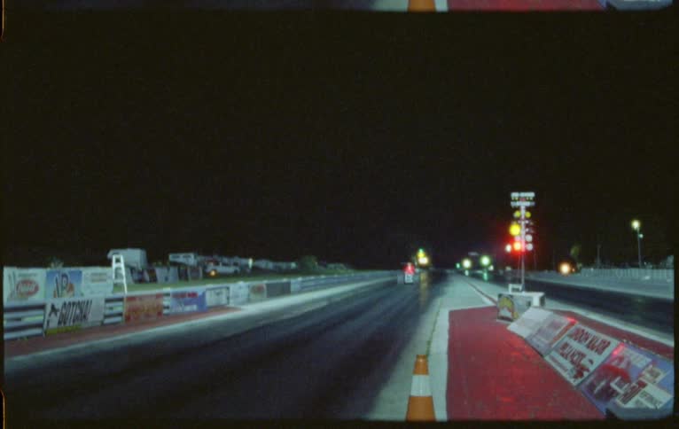 A color race car takes off down a track lined with ads and signs