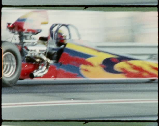 Two vehicles drag racing on a track with trees the sky and clouds in the background