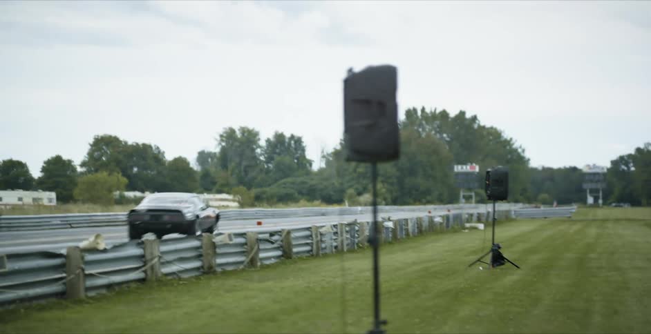 Two muscle cars with flame designs race on a straight track