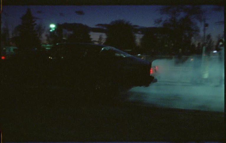 A sports car spinning its tires and peeling out at night