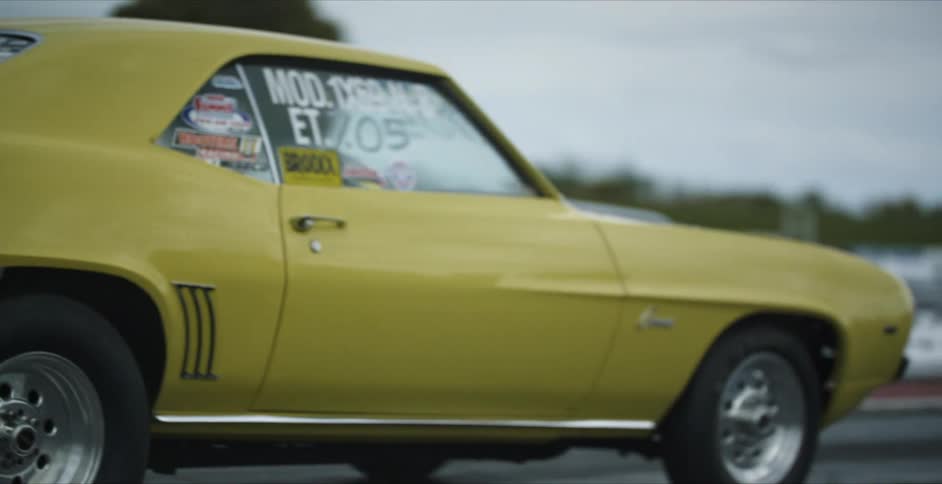 A yellow race car inches up in the road