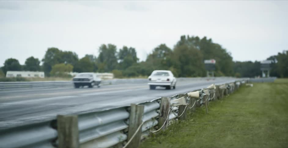 Two cars speeding down a racetrack in the daytime